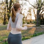 A woman jogs in a park during sunset, enjoying an outdoor fitness routine.